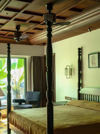 A wider view of the master bedroom, showing the coffered wood ceiling and the view to the lush greenery outside.