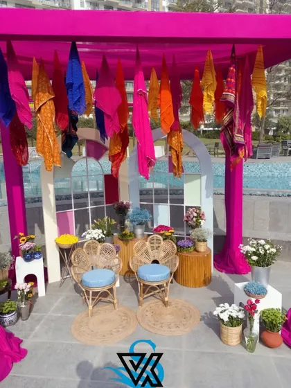 A vibrant and colorful photo booth we created for a poolside Haldi function. The setup includes peacock chairs and a canopy of bright sarees, making for a fun and memorable spot.