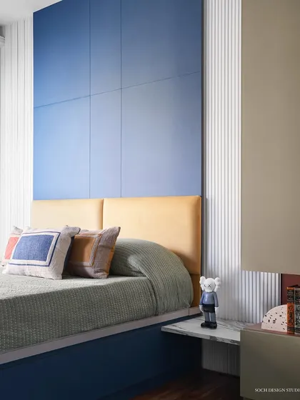 The kids' bedroom is a vibrant and geometric space designed for a 10-year-old. The color palette of blue, yellow, and magenta creates a playful atmosphere, with a custom headboard and ample toy storage.
