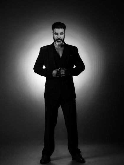 A full-length shot that commands attention. We used a single spotlight to create this dramatic effect, isolating the subject in a halo of light to emphasize his powerful stance and sharp suit.