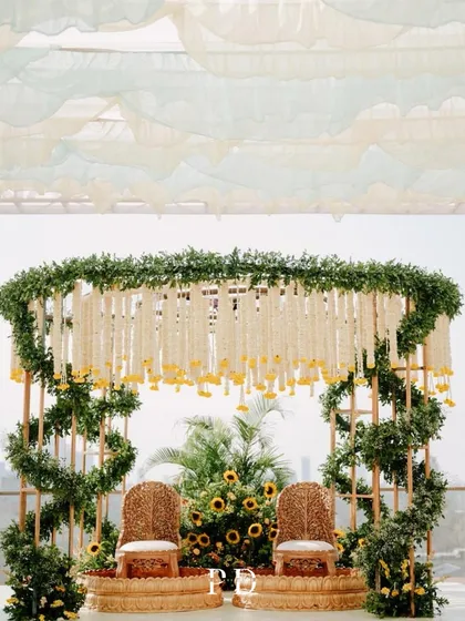 A beautiful Haldi mandap with a canopy of hanging tuberoses and marigolds, set against a backdrop of lush greenery. The design is both traditional and refreshingly light.