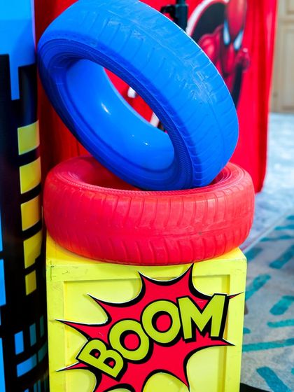 Themed props like these colorful tires and "BOOM!" signs are used throughout the venue to enhance the superhero decor.
