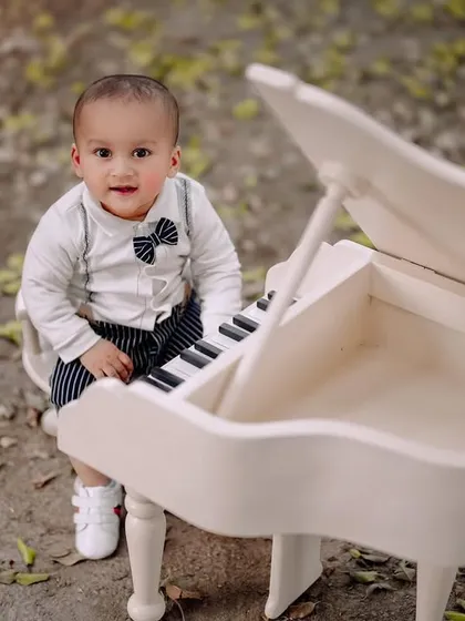 A sweet, direct look from a little boy at his piano. His smart outfit with the bowtie and suspenders makes this a very dapper portrait.