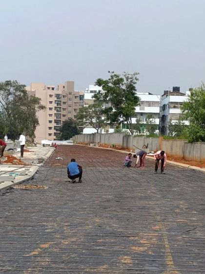 A wide view of our crew laying paving blocks for a large driveway or road surface. This demonstrates the scale of our on-site execution and management for large plotted development projects.