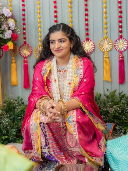The bride during her Bane Bithai ceremony. For this traditional event, we chose a heavily embroidered pink and purple suit with beautiful gota patti work, paired with floral jewelry.