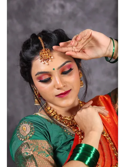A graceful portrait with the model's eyes closed, focusing on the makeup and the traditional maang tikka and necklace.