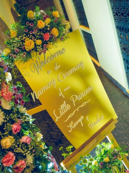 A welcome sign for a naming ceremony, beautifully decorated with fresh flowers, setting a warm and inviting tone for arriving guests.