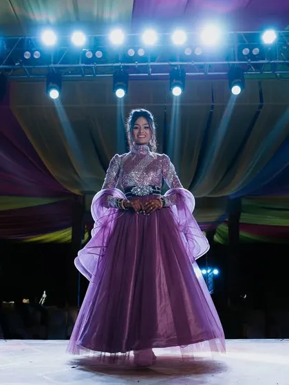 A stunning solo portrait of the bride on the Sangeet stage, illuminated by spotlights.