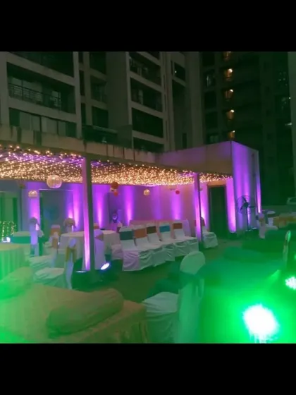 An outdoor venue setup at night, showing how we use a combination of fairy light ceilings and colorful uplighting to create a vibrant and festive party atmosphere.