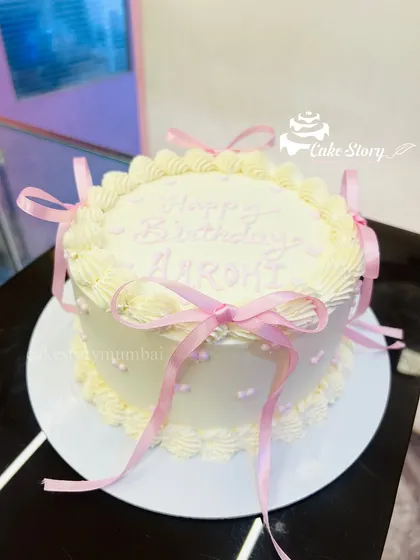 A trendy and delicate bow cake. The simple white cake is adorned with pretty pink ribbons, giving it a soft and classic coquette aesthetic.