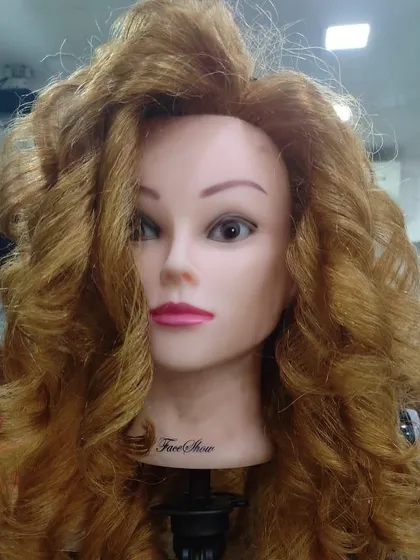 A front view of the finished curly style by a student. They've created a glamorous look with lots of volume and definition.