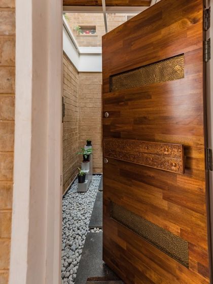 Another view of the Vruksha door, opening into a narrow, light-filled passage. The custom handle, made from a reclaimed carved beam, is a centerpiece of the entrance experience.