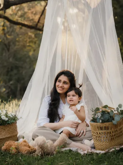 A mother and daughter enjoying their time in a beautiful teepee setup in the park.