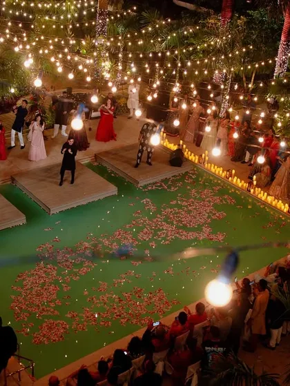 An epic sangeet setup over a pool in Goa, with the stage built on the water and the entire area illuminated by strings of fairy lights.