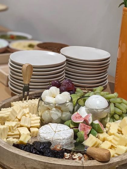 Another view of a popular cheese board setup, with stacks of plates ready for guests to serve themselves. I ensure every detail, including the serving ware, is taken care of.