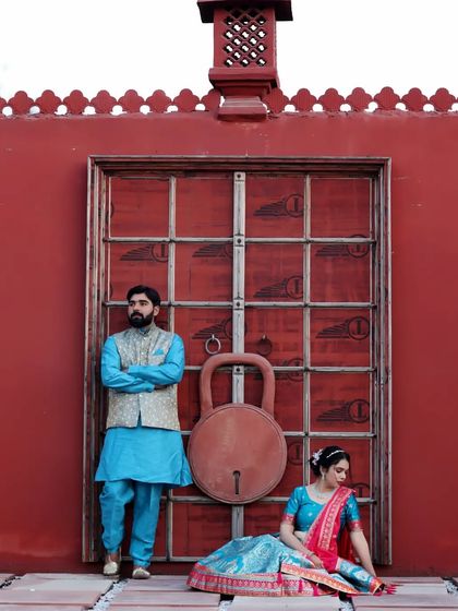 A stylish portrait of a couple in traditional wear against a bold red wall. The composition and colors make this a very striking image.