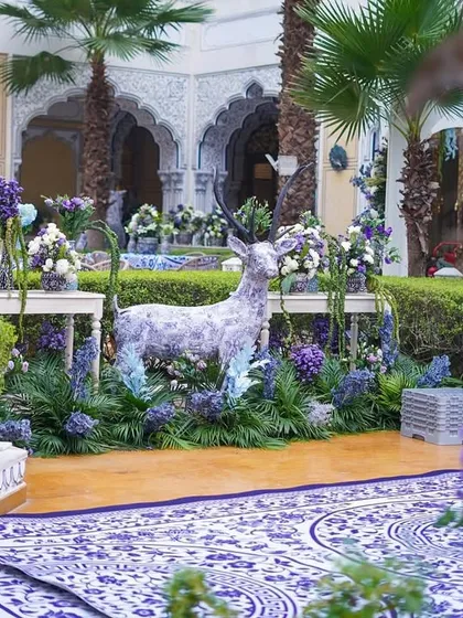 A whimsical touch with a deer statue covered in the event's signature blue and white pattern, surrounded by a bed of purple and blue flowers.