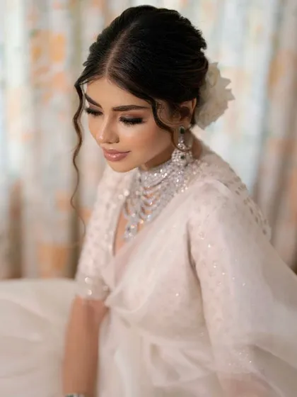 For a soft and romantic reception look, I crafted this textured messy bun. The face-framing wavy tendrils and the fresh white rose create a dreamy, effortless style that looks stunning in photos.