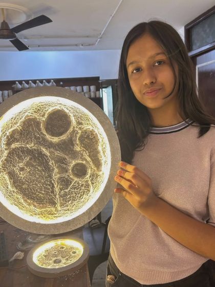 A student proudly holds up her large, detailed moon lamp, a testament to the amazing things you can create here.