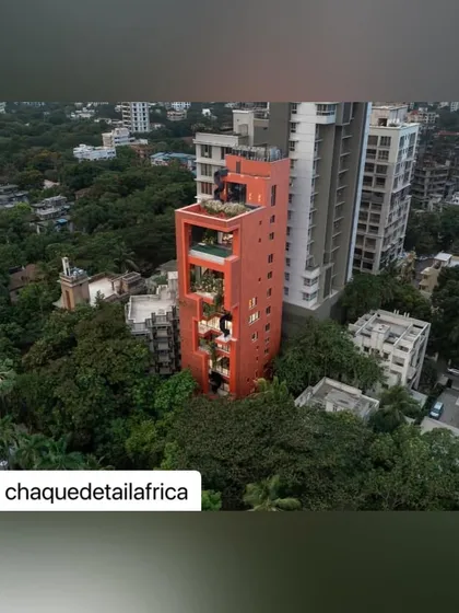 This aerial shot captures the full context of the Sarvasva tower. The rooftop greenery and the vertical garden running down the facade demonstrate a comprehensive approach to urban landscape design.