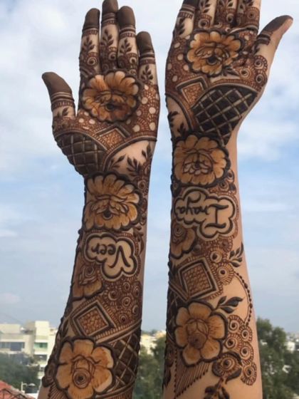 Another angle of the bridal mehendi with the names Veer and Inaya, set against the sky.