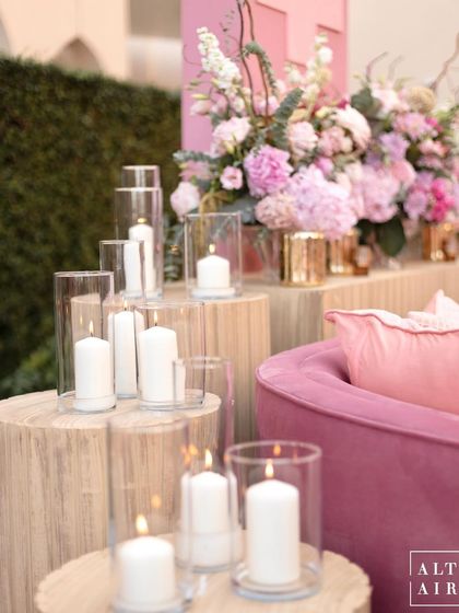 Candlelight details from the 'Echoes of Pink' wedding. The soft glow of candles on wooden logs added a rustic, warm touch to the otherwise glamorous pink setting.