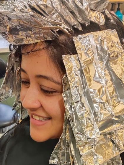 A happy client during her hair colouring session. The foils are meticulously placed to achieve the desired highlights and overall look.