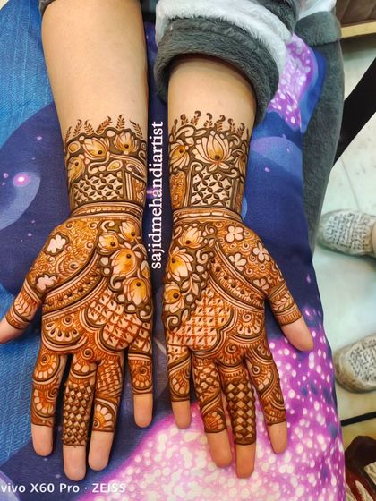 This design features heavy checkerboard patterns (jaali work) on the fingers and palms, combined with delicate lotus motifs on the wrist. It's a classic style that always looks elegant.