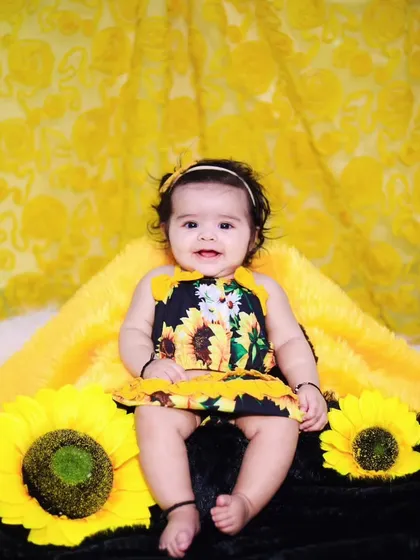 A bright and cheerful sunflower-themed shoot with a baby girl in a matching dress.