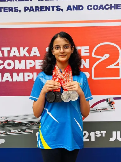 A portrait of our champion Indu, showcasing the multiple medals she won at the Karnataka State Shooting Competition through sheer hard work and precision.