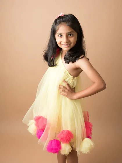 A young girl poses confidently in a bright and colorful dress. A beautiful portrait that captures her vibrant personality.