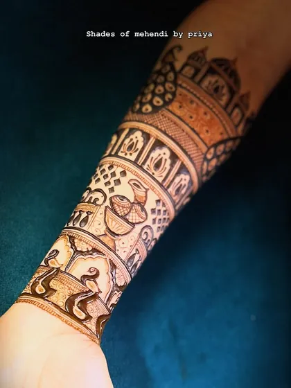 A close-up of the intricate bands on the forearm, featuring diyas, peacocks, and geometric patterns.