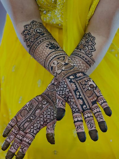 A beautiful crossed-hands pose, showing the symmetry and detail of the bridal mehendi.