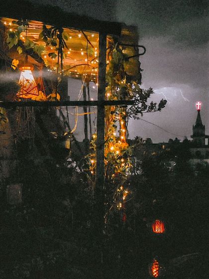 A perfectly timed photo capturing a flash of lightning behind the garden. It shows the dramatic beauty of nature against the calm, steady glow of the garden lights.