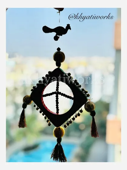 A silhouette of the kite-themed wall hanging against a window, showing its unique shape and the delicate bird detail at the top.