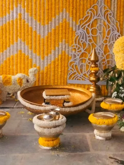 A beautiful Haldi ceremony setup with a marigold and jasmine flower backdrop. The decor also features a peacock and elephant made of flowers.