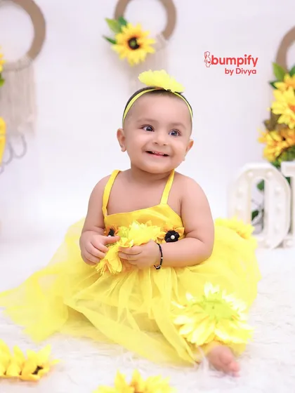 Our little sunshine. This baby girl is all smiles during her sunflower themed first birthday photoshoot. The bright yellow dress and flowers create such a happy, vibrant image.