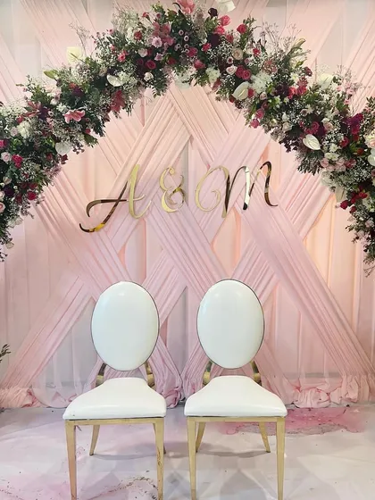 A beautiful floral arch for Anam and Musthaqeem's Baat Pakki. The combination of pink draping, a lush arch of flowers, and the couple's initials created a perfect backdrop for their special day.