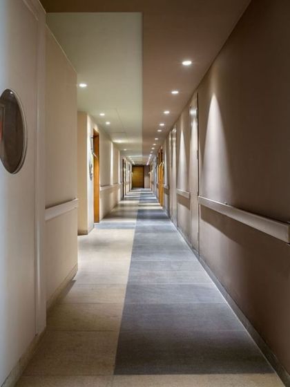 A long corridor in a hospitality setting, where varied flooring patterns and thoughtful lighting break up the length and create a more engaging pathway.