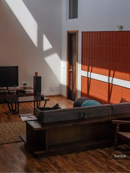 Sunlight streams into the living room, highlighting the warm wood flooring and terracotta wall. This demonstrates our focus on creating bright, naturally lit interiors.