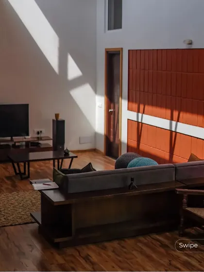 Sunlight streams into the living room, highlighting the warm wood flooring and terracotta wall. This demonstrates our focus on creating bright, naturally lit interiors.