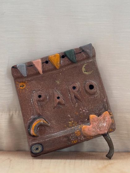 A whimsical, book-shaped hanging decor piece made by a student. The colorful flags and imaginative details make this a truly unique work of art.