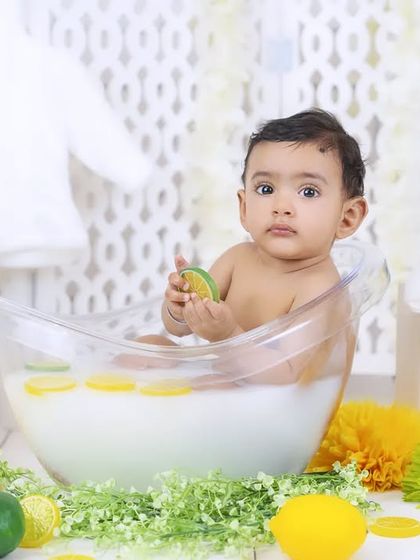 A baby enjoys a relaxing and fun milk bath, surrounded by fresh citrus and flowers.