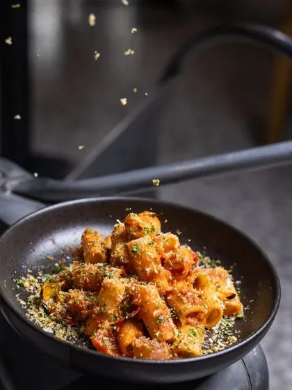 A delicious bowl of Rigatoni with arrabbiata sauce and a sprinkle of herb crumbs, perfect for a satisfying meal.