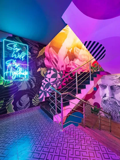 The eclectic mix of classical sculpture motifs, modern graphics, and neon lighting on this staircase wall creates a unique visual narrative. It’s a perfect example of how we blend different styles to create a cohesive and exciting design.