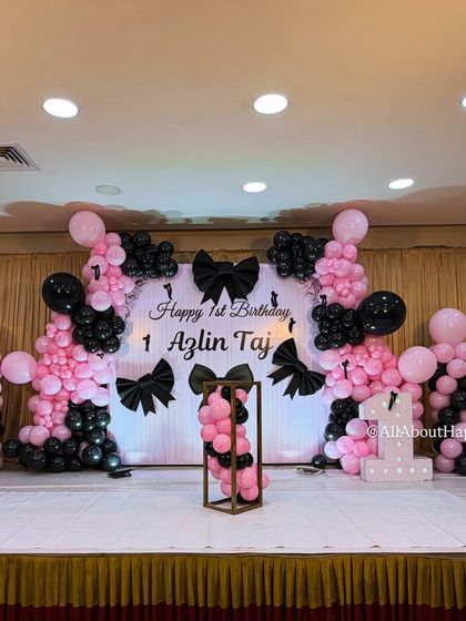 We love bringing Pinterest-worthy ideas to life, like this chic bow-themed first birthday. The stage is decorated with pink and black balloon arrangements and large, elegant black bows.