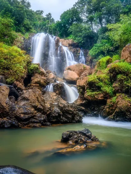 A long exposure of Shirley Falls in the Western Ghats, focusing on the details of the water flowing over the rocks into a green pool below.