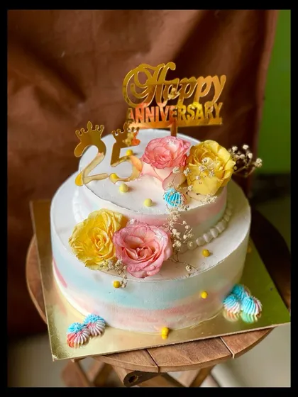 A beautiful two-tier cake for a 25th anniversary. I used a pastel watercolor buttercream effect and decorated it with fresh roses and a "Happy Anniversary" topper.