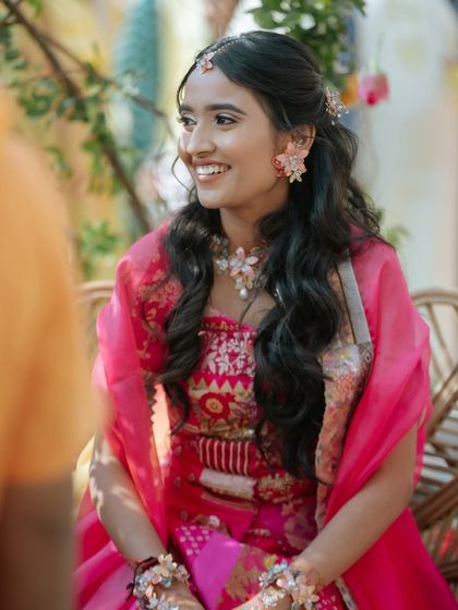 A candid photo of a bride at her Haldi ceremony. Her hair is styled in a simple half-updo with loose waves, giving her a natural and radiant look.