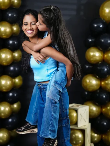A sweet moment between two sisters, with the younger one giving her older sister a kiss on the cheek during their shared studio session.
